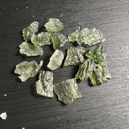 Sammlung kleiner Besednice Moldavite auf dunklem Holz grün glasig | Happy Minerals