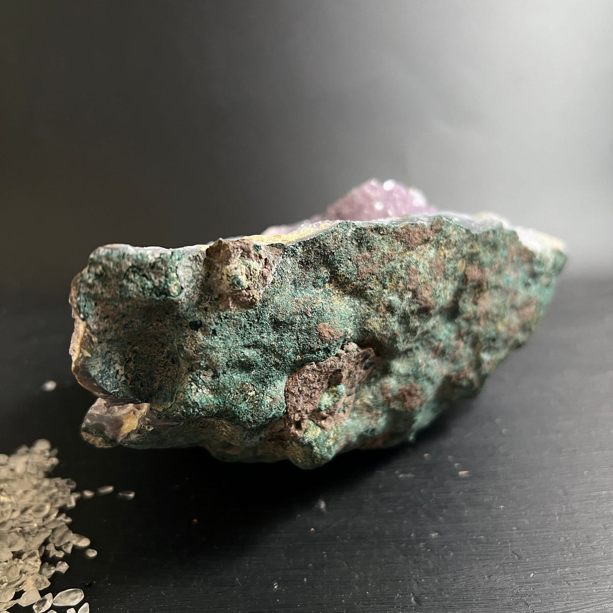 Rohstein mit moosgruener Matrix, rostbraunen Flecken und violetten Amethystkristallen an der Oberkante | Happy Minerals
