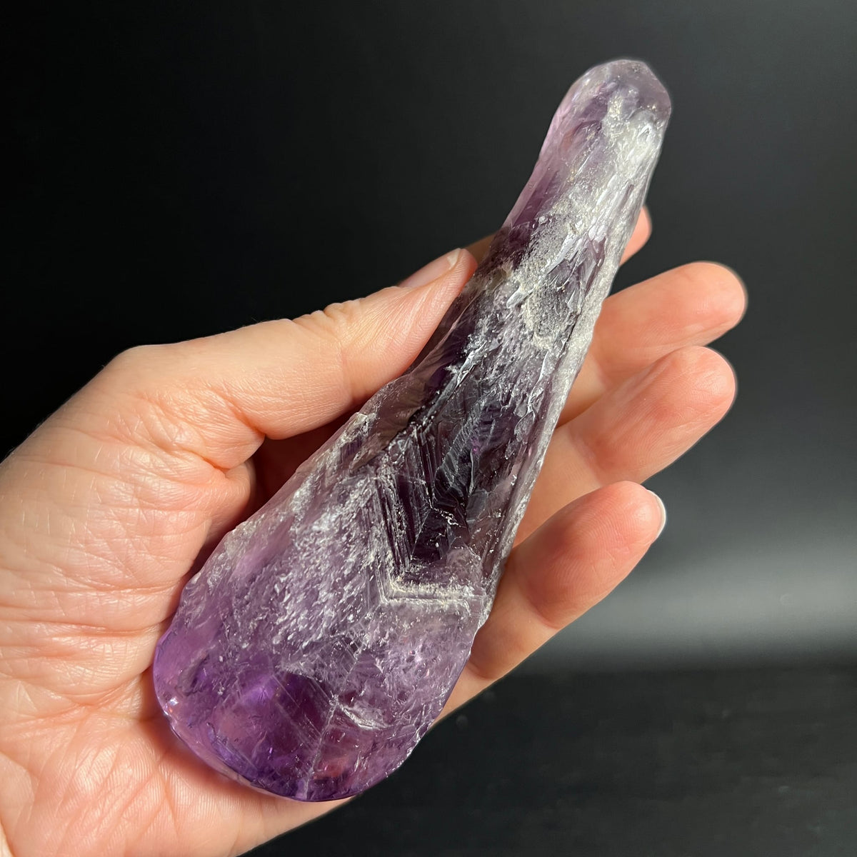Amethyst Massagestab quer in Hand | geschwungene Form | violette Farbverläufe | Happy Minerals