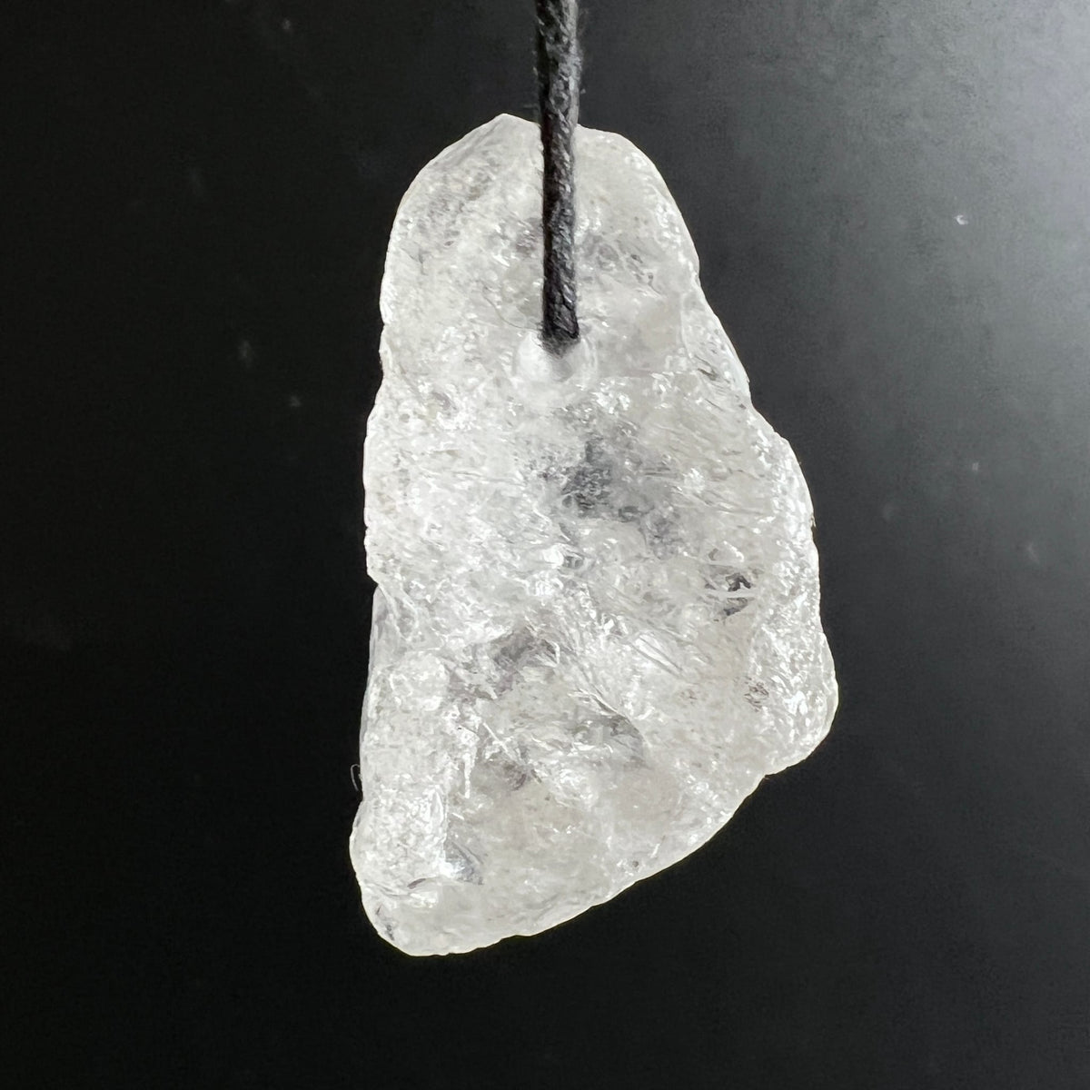 Roher Bergkristall Anhaenger, milchig-transparent mit facettierter Oberflaeche und Rissen, an schwarzer Schnur | Happy Minerals