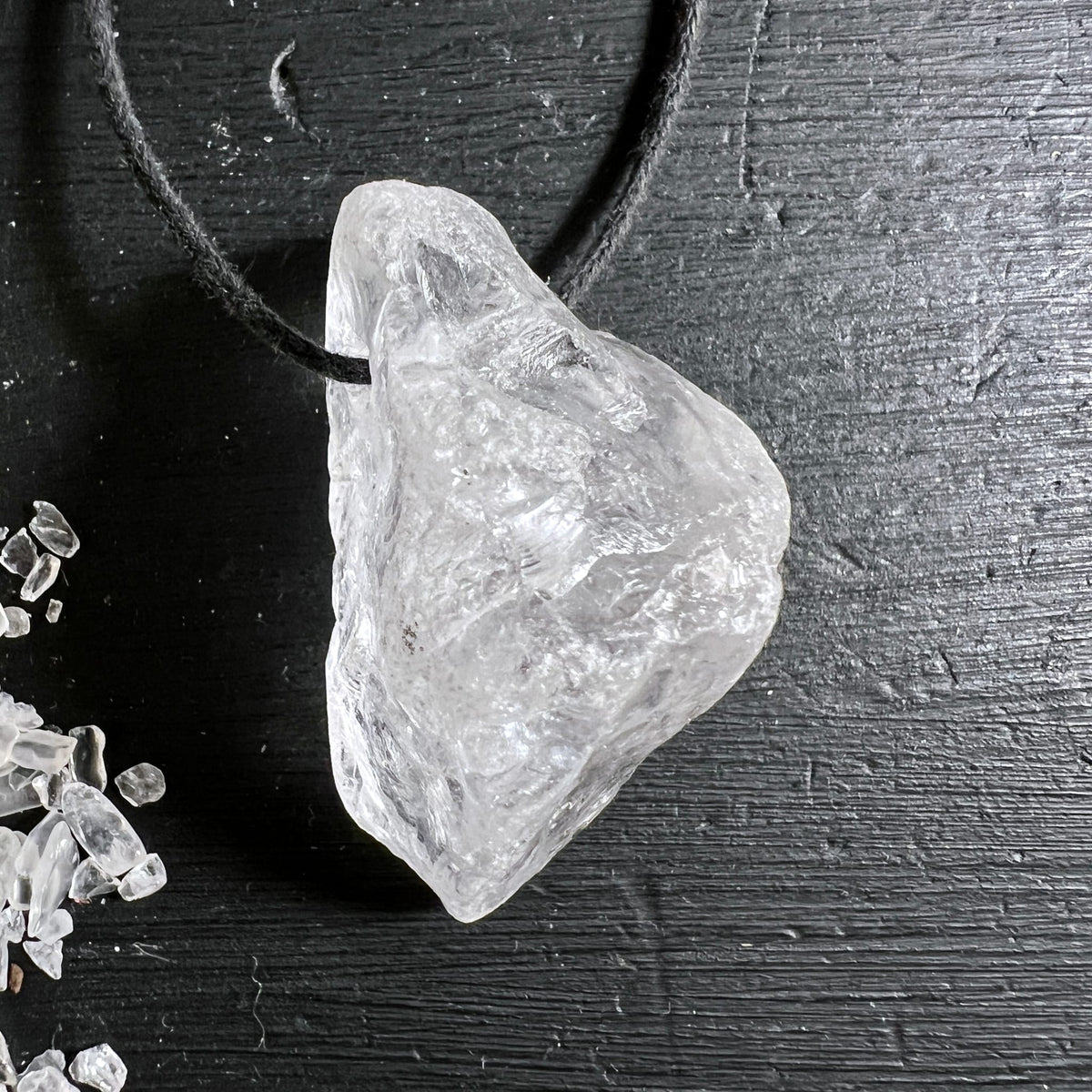 Roher Bergkristall Anhaenger transparent-weiss mit rauer Oberflaeche und Lichtreflexen, an schwarzer Schnur | Happy Minerals