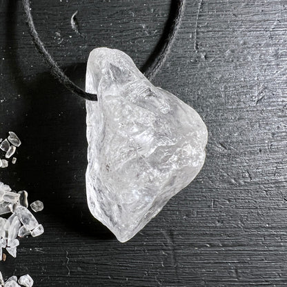 Roher Bergkristall Anhaenger transparent-weiss mit rauer Oberflaeche und Lichtreflexen, an schwarzer Schnur | Happy Minerals