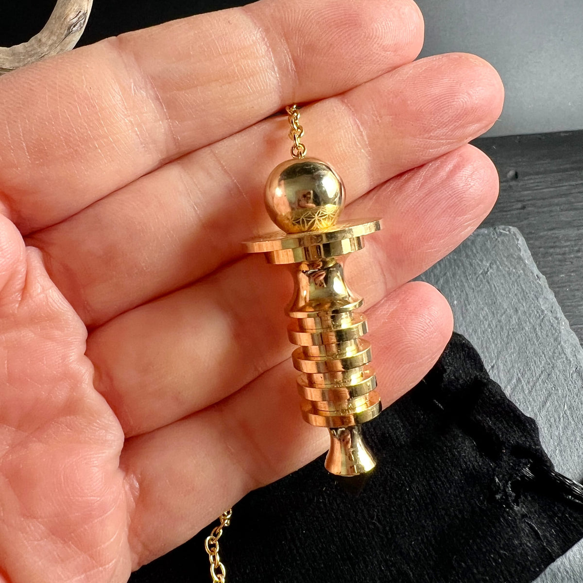 Isis Pendel Messing vergoldet | in der Hand gehalten | Größenvergleich | Spiralringe & Kugelkopf | Happy Minerals