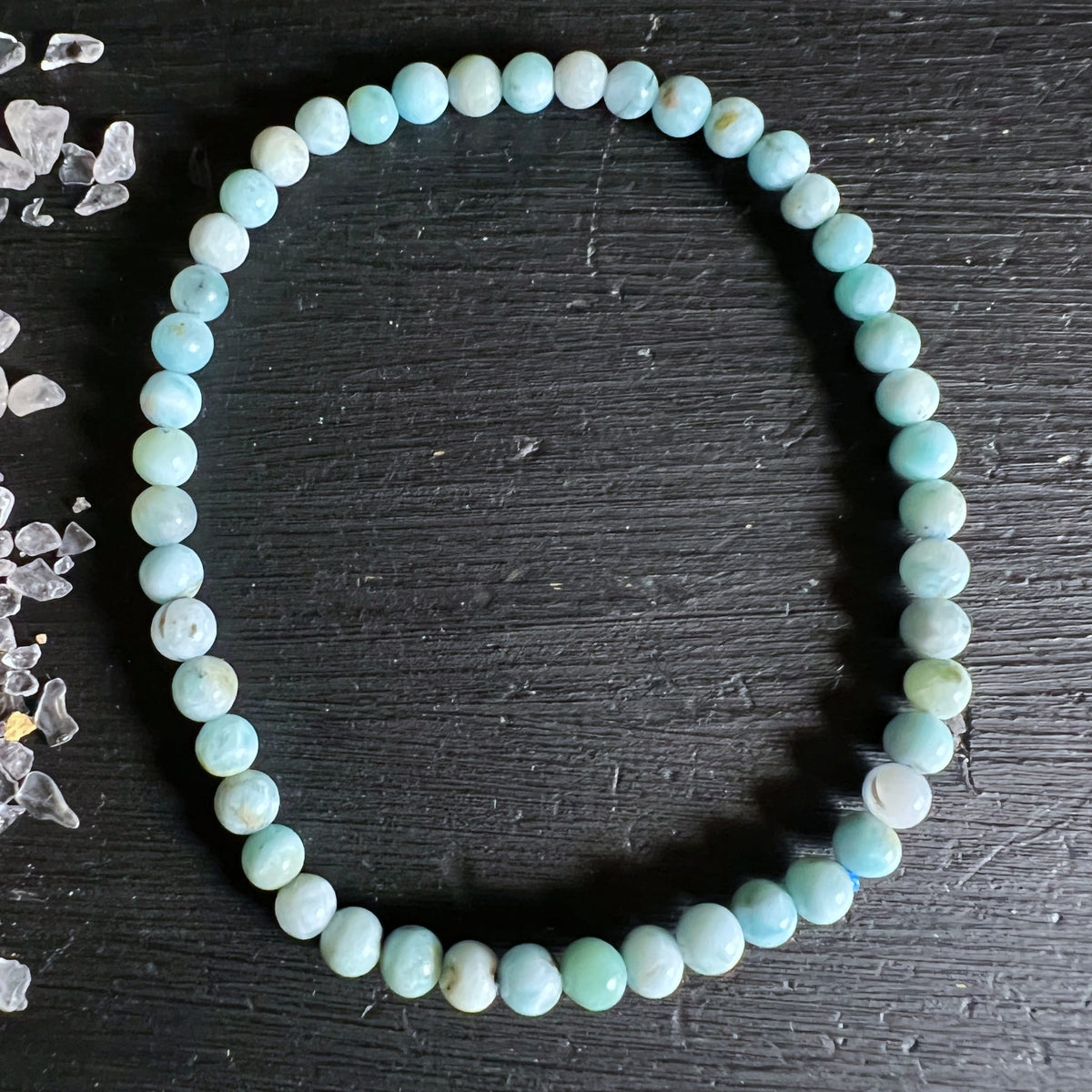 Larimar Armband mit runden Perlen in hellblau-tuerkis und cremeweissen Maserungen, auf dunklem Holz | Happy Minerals