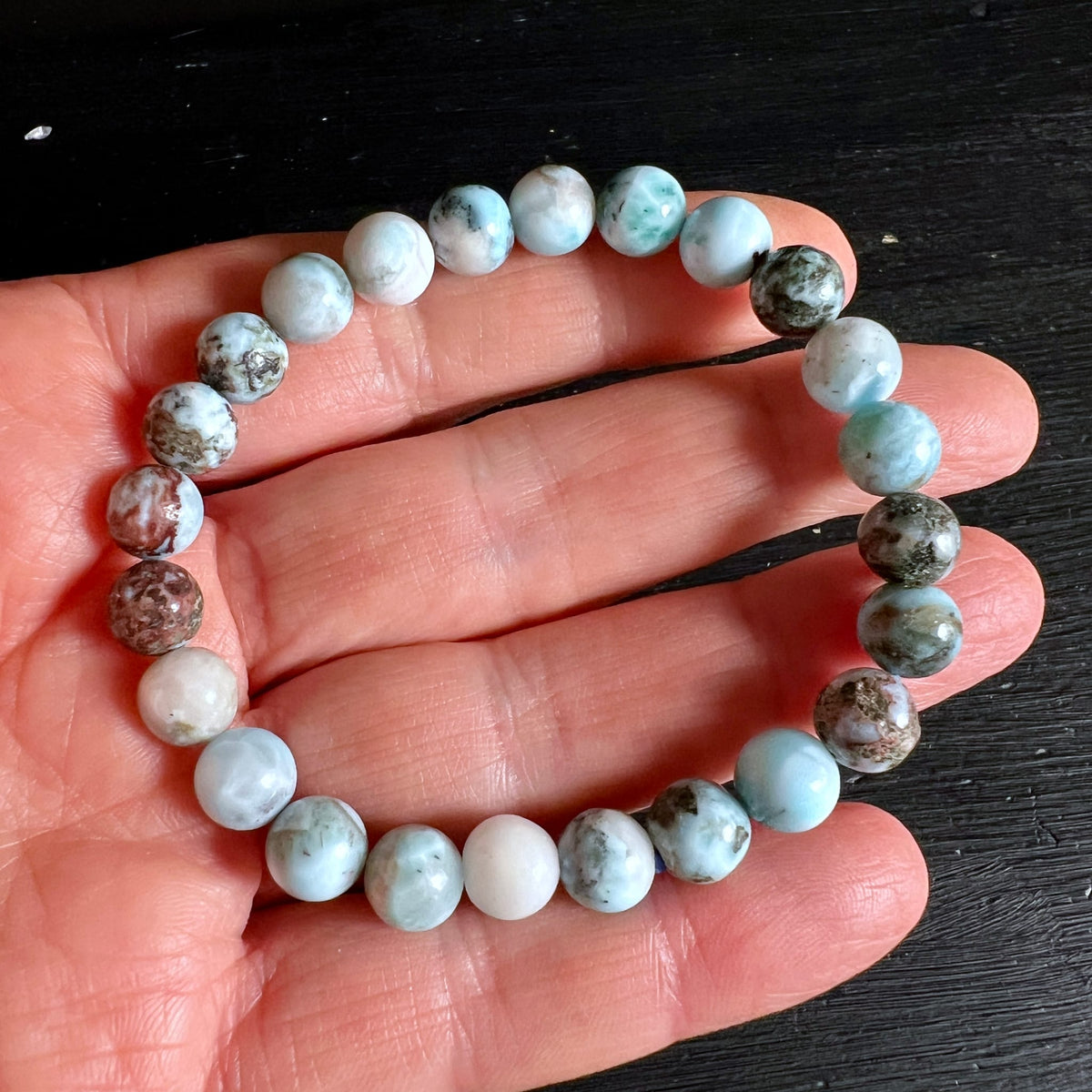 Larimar Armband aus runden Perlen, weiss-tuerkis marmoriert mit braunen Einschluessen, auf Hand | Happy Minerals