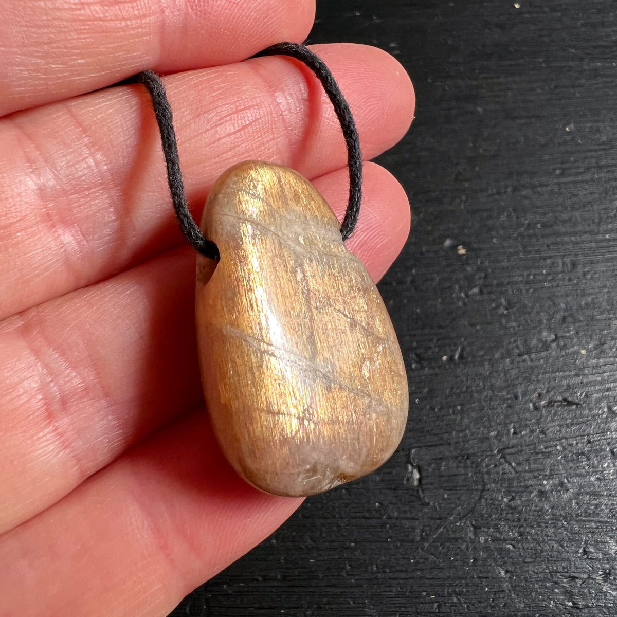 Mondstein Anhaenger goldbraun schimmernd, tropfenfoermig poliert mit feinen Linien an schwarzer Kordel | Happy Minerals