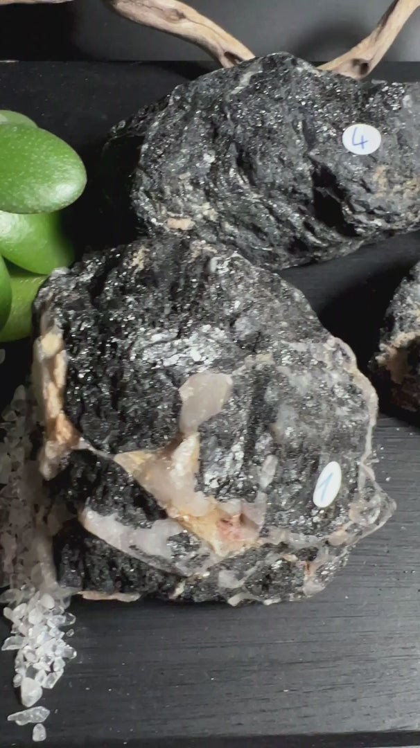 Fünf schwarze Turmalin Rohsteine aus Brasilien mit Quarz auf dunklem Untergrund