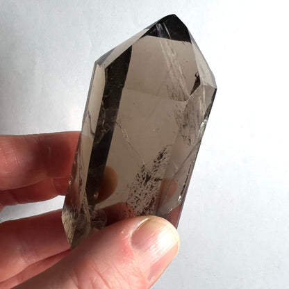 Rauchquarz | Nahaufnahme in Hand | facettierte Spitze | rauchbraune Einschlüsse | Unikat | Happy Minerals