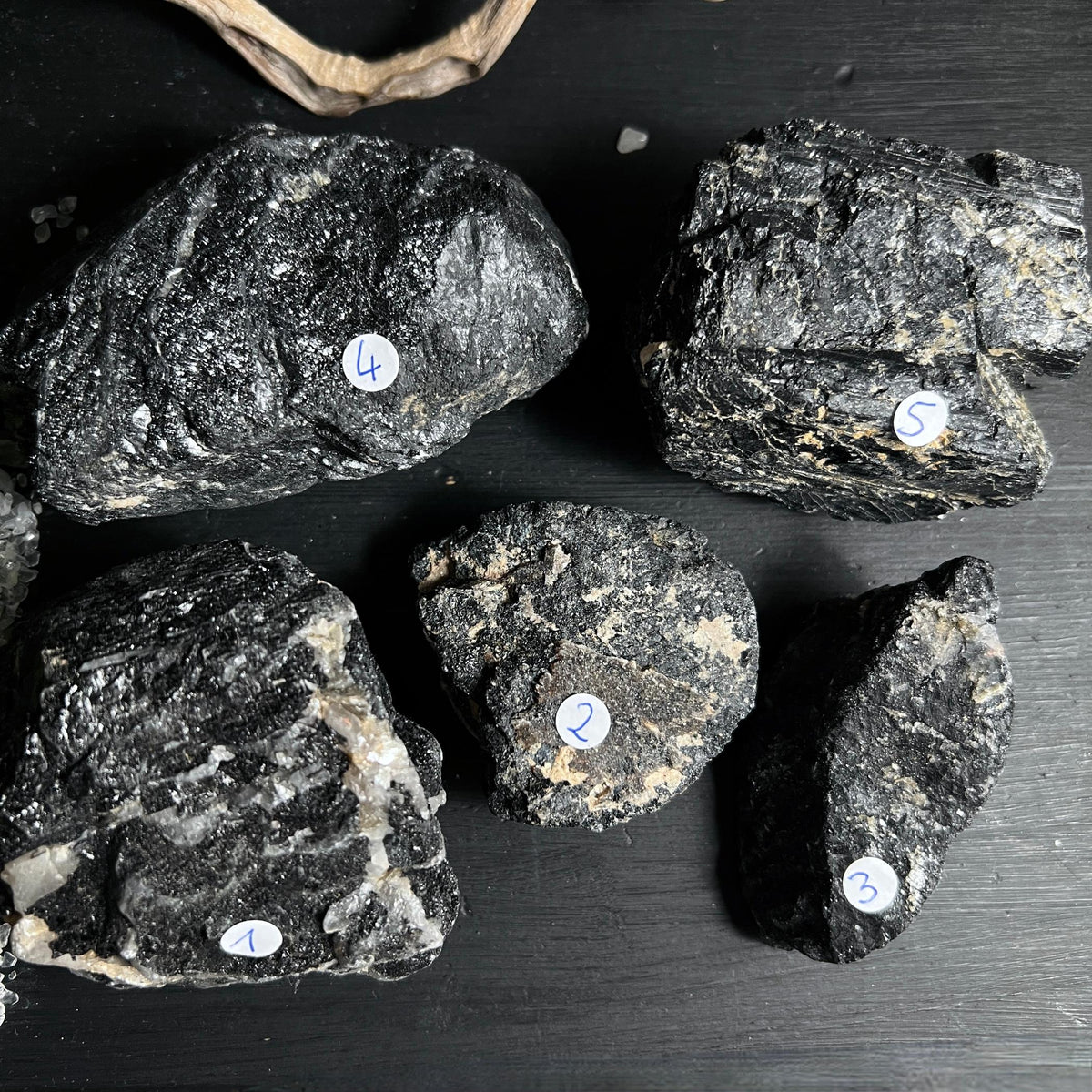 Fünf schwarze Turmalin Rohsteine aus Brasilien mit Quarz auf dunklem Untergrund