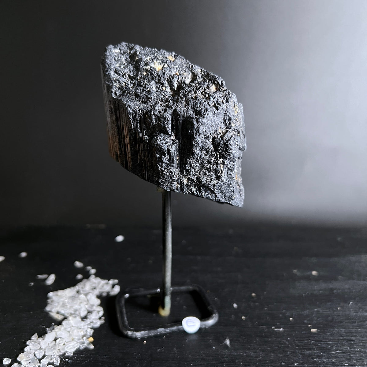 Schwarzer Turmalin Rohstein mit faserig-glänzender Bruchkante auf Metallständer | Happy Minerals