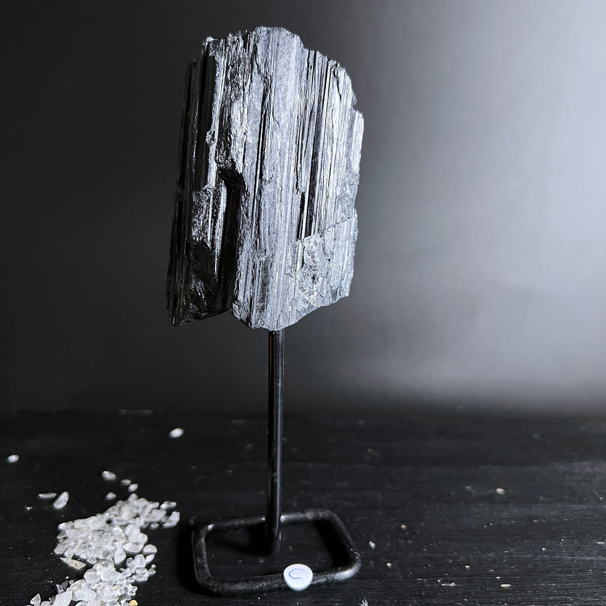 Schwarzer Turmalin Rohstein mit silbrig-grauen Faserstrukturen auf Metallständer | Happy Minerals