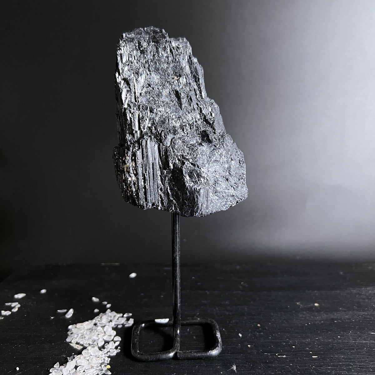 Schwarzer Turmalin Rohstein mit metallisch glänzenden Faserstrukturen auf Metallständer | Happy Minerals