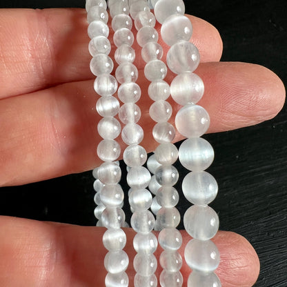 Selenit Armband aus milchig-transparenten Perlen 4-6mm mit feinen Glanzstreifen, auf Fingern drapiert | Happy Minerals