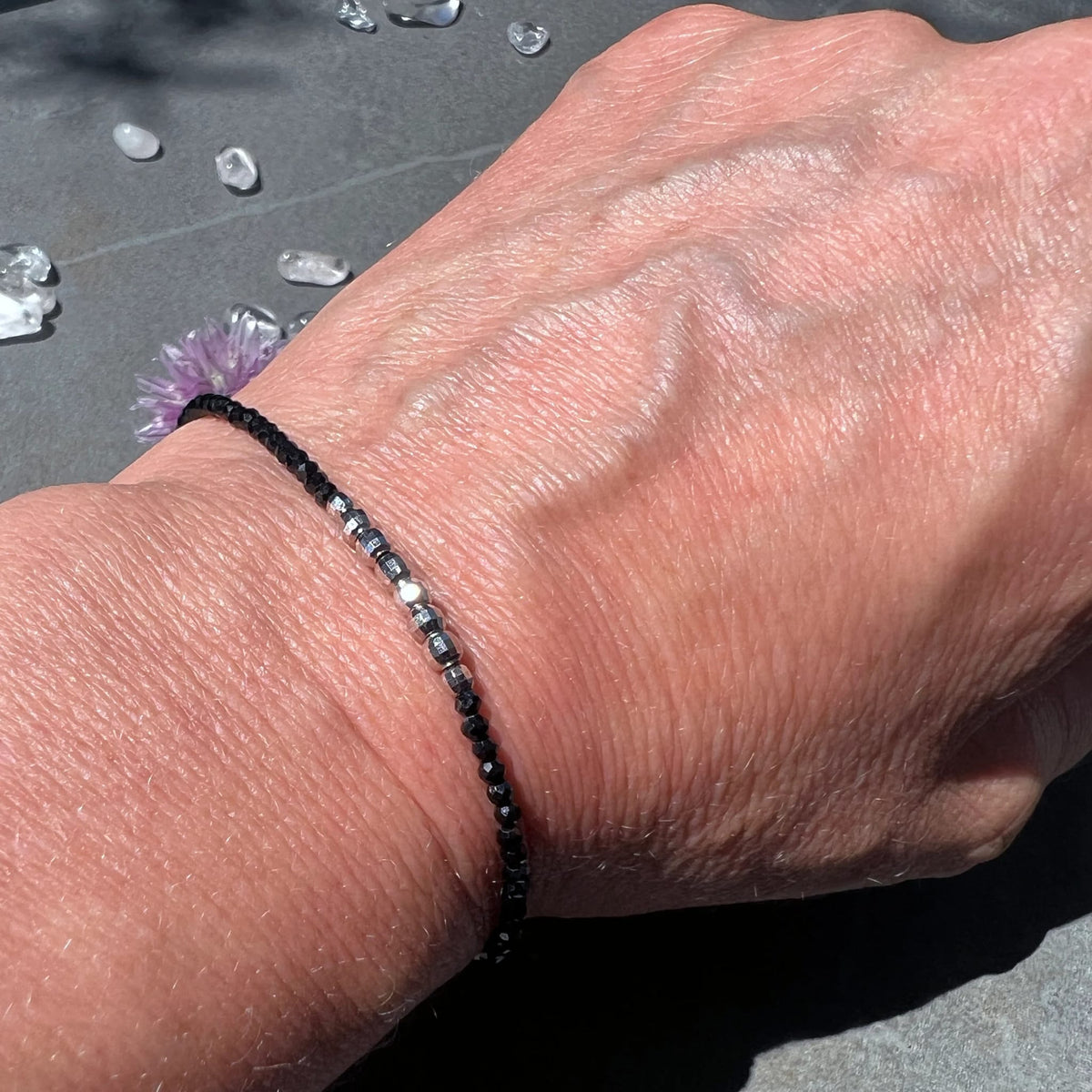 Elegant | getragenes | Spinell-Armband | am Handgelenk | mit Bergkristallen | im Hintergrund | Happy Minerals