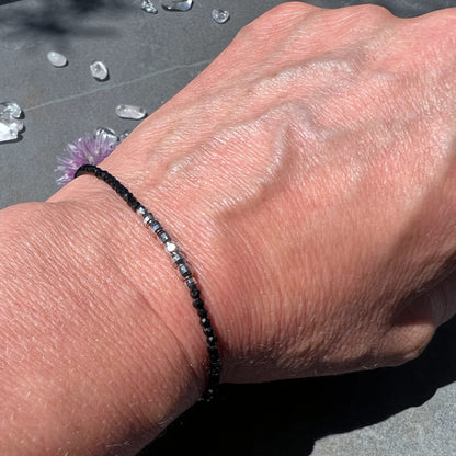 Elegant | getragenes | Spinell-Armband | am Handgelenk | mit Bergkristallen | im Hintergrund | Happy Minerals