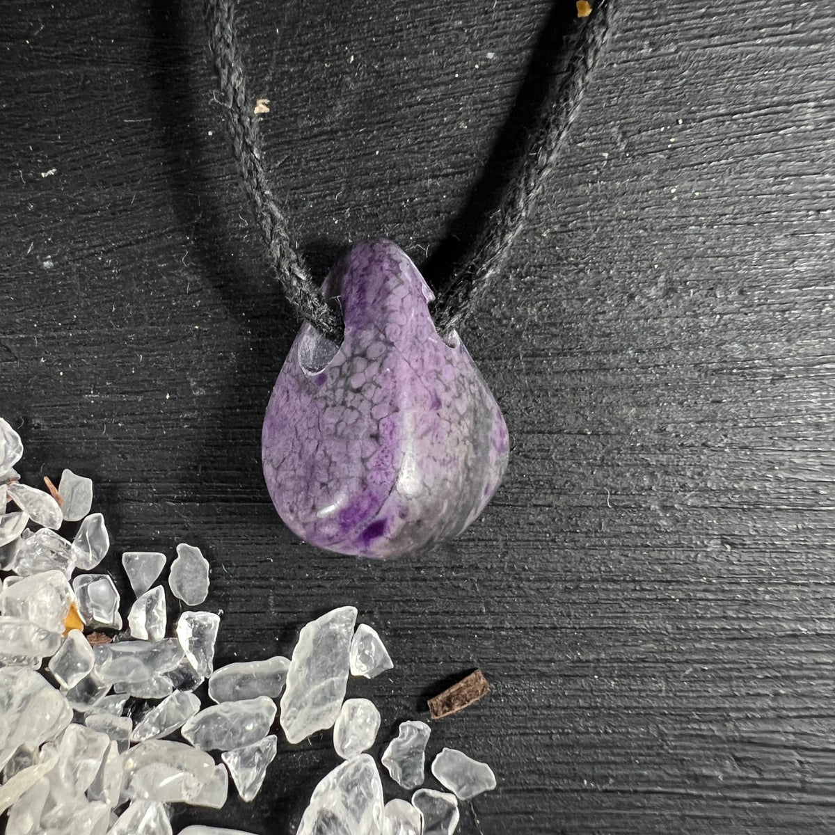Sugilith Anhaenger tropfenfoermig, violett-grau marmoriert mit dunklen Adern, an schwarzer Kordel | Happy Minerals